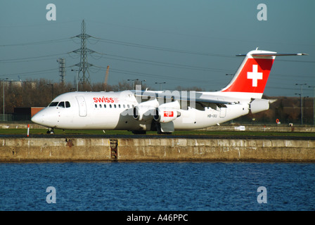 Swiss International Airlines aircraft on runway beside redundant King George V dock waters City Airport Silvertown East London England UK Stock Photo