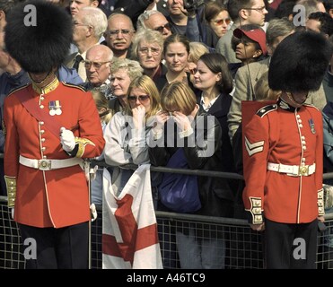 Crowd of people line the route of the Queen Mother s funeral procession guarded by members of the Guards regiment The Mall  Stock Photo