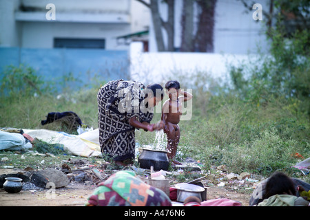 Mother washing small child on rubbish tip, Rupena Agrahara Hosur Road Area Bangalore, India Stock Photo