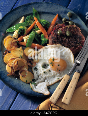 A burger fried egg and vegetables on blue background editorial food Stock Photo