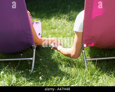 Young couple relaxing on lounge chairs Stock Photo