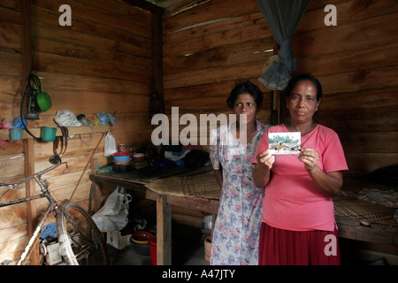 Two sisters display a photograph taken of their destroyed house almost one year after the tsunami struck Sri Lanka Stock Photo