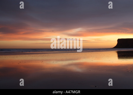 beach view at Saltburn in North Yorkshire with pre sunrise colours in sky reflected on wet sand looking towards Hunt Cliff Stock Photo