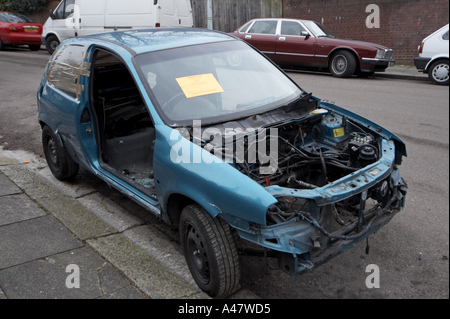 Abandoned Blue Vauxhall vandalised and strip of parts wrecked car left on suburban London street with Council disposal warning  Stock Photo