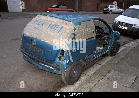 Abandoned Blue Vauxhall vandalised and strip of parts wrecked car left on suburban London street with Council disposal warning  Stock Photo