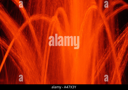 Water fountains at night bathed in orange light Stock Photo
