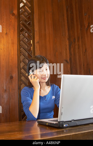 Taiwan, Woman Talking On Phone And Using Laptop Stock Photo