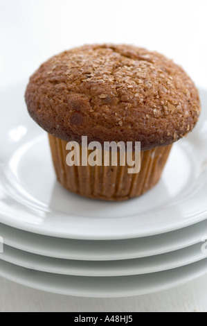 Cinnamon bran muffin on stack of white plates with cup of black coffee Stock Photo