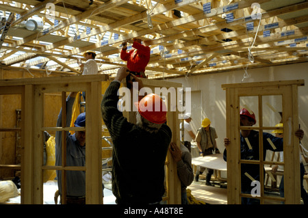 Construction workers in hard hats installing window and door frames and ceiling joists in a church hall Stock Photo
