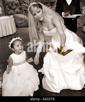 Flower girl with bride releasing butterfly Stock Photo