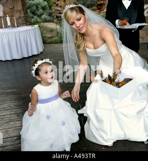 Flower girl with bride releasing butterfly Stock Photo