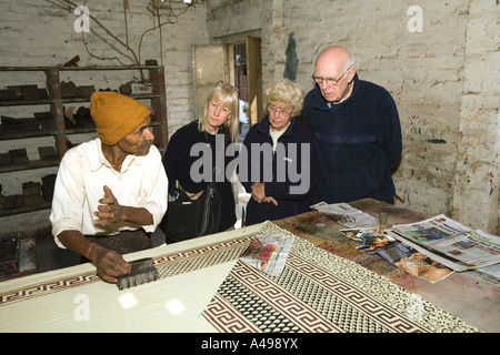 India Rajasthan Sanganer near Jaipur group of older western visitors watching textile block printer printing Stock Photo