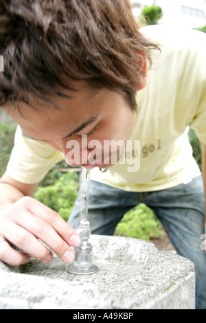Close up of a young man drinking ^water from a faucet Stock Photo