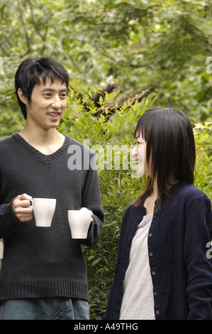 Young woman standing with a young man holding coffee cups Stock Photo