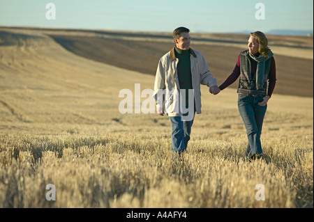 Couple walking through fields of cut grass in Fall Colorado early morning Stock Photo