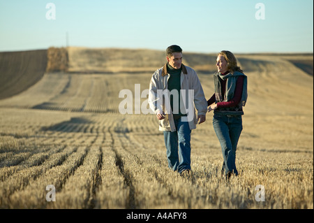Couple smiling walking through fields of cut grass in Fall Colorado early morning Stock Photo