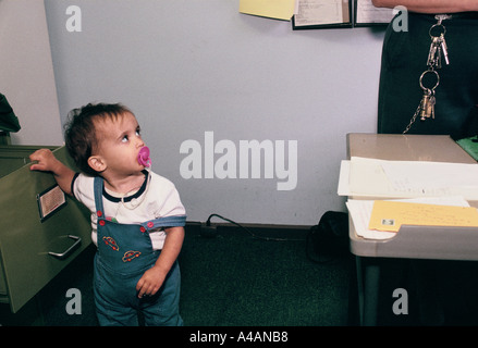 A child in the prison office looks at a prison officer who is wearing a set of shiny keys. Stock Photo