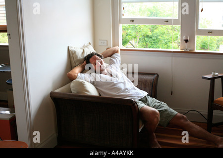 A middle aged healthy man relaxes in an apartment window seat Stock Photo
