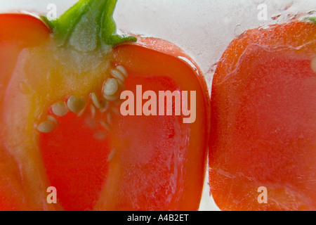 Close-up of two red pepper halves showing the inside with seeds frozen in ice Stock Photo