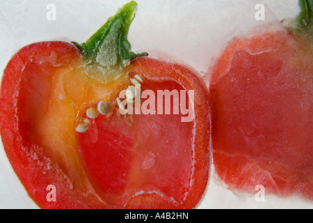 Close-up of two red pepper halves showing the inside with seeds frozen in ice Stock Photo