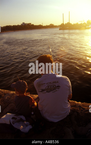 Silhouette of father and son fishing at sunset in summer on the sea ...