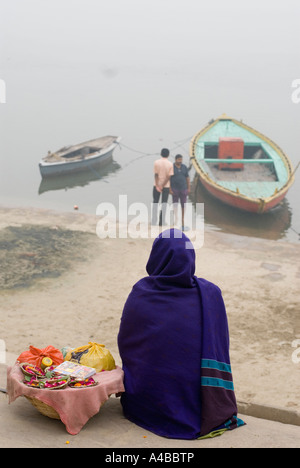 Indian woman wrapped in her sari with her head covered contemplating or meditating on the banks of the Ganges at Varanasi Stock Photo