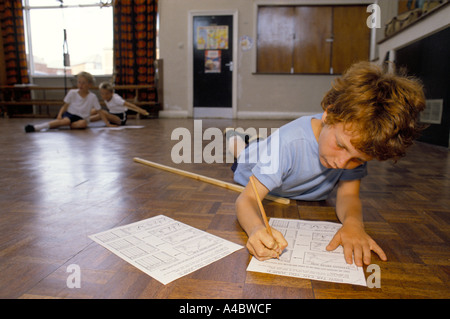 SCHOOL BOY MAKING NOTES ON EXERCISES DURING P.E. LESSON IN A PRIMARY SCHOOL Stock Photo