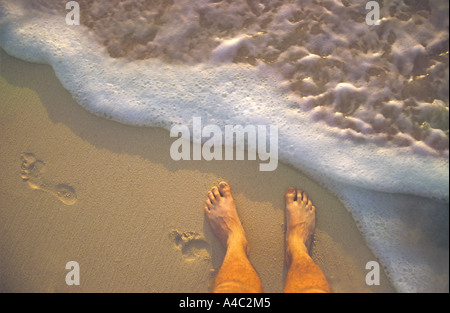 Mans Feet On Beach While Waves And Foam Splash On Sand Close Up, Hawaii USA Stock Photo