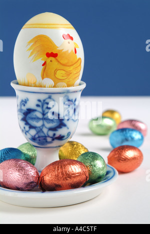 Painted and chocolate Easter eggs in and around a blue and white egg cup