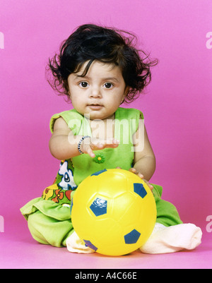 A little girl with a yellow plastic ball Stock Photo