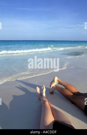 Couples legs outstretched on beach with ocean in background Cancun Mexico Caribbean Stock Photo
