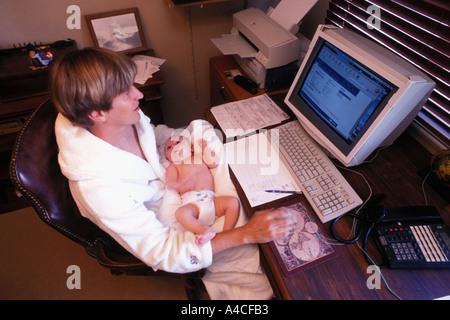 Modern dad with baby on lap doing computer work at home Stock Photo