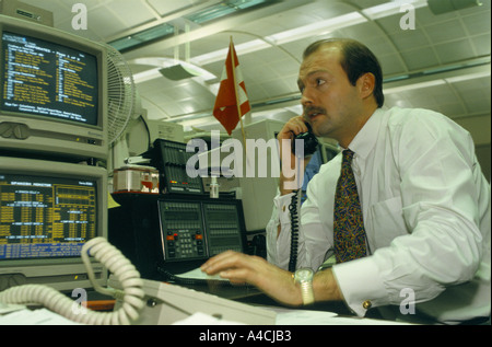 trading floor london 1994 broker in shirt tie talks on telephone in front of 2 screens of computer at his desk Stock Photo
