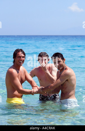 Three young men playing in the water Stock Photo