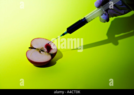 Syringe full of red liquid injecting apple Stock Photo