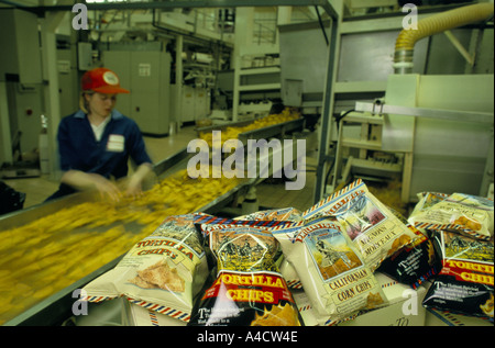 PHILEAS FOGG FACTORY PRODUCING TORTILLA CHIPS, EX STEEL WORKS, DURHAM, ENGLAND. WORKER NEXT TO CONVEYOR BELT WITH TORTILLA CHIP Stock Photo