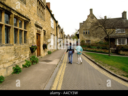 UK Gloucestershire Chipping Camden two female visitors walking along the High Street Stock Photo