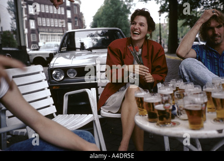 A woman with two red roses in her hands having a laugh at a cafe terrace, Holland Stock Photo