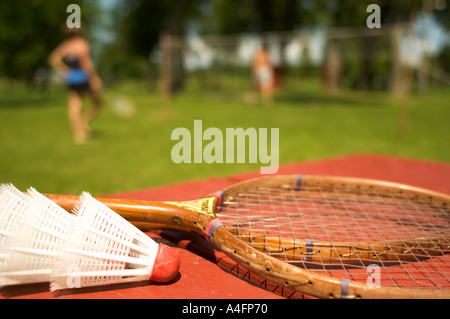 Badminton racquet and shuttlecocks sitting on table with people playing in background Stock Photo