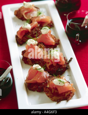 Dish of canapes mini rosti topped with smoked salmon and a little sour cream garnished with dill Stock Photo