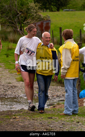 A race marshal helps an injured runner at Abergwesyn ford in the annual Man v Horse race at Llanwrtyd Wells Powys Mid Wales UK Stock Photo