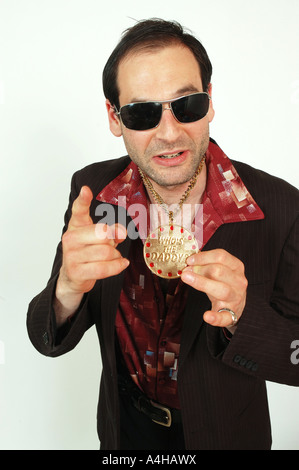 A sleazy looking man holding a medalion pointing to camera Stock Photo