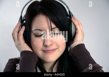 Young woman with headphones on enjoying music with eyes closed Stock Photo