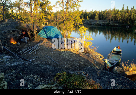 Man at campfire on a lakeshore, Northwest Territories, Canada Stock Photo