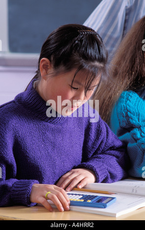 Asian American female student using calculator to do math work in class Stock Photo