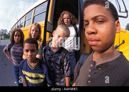 Portrait of Latino Caucasian and African American students in front of school bus. Stock Photo