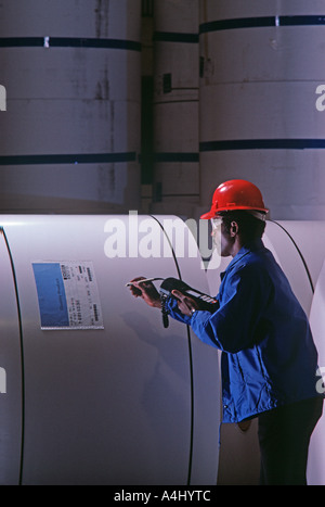 Male warehouse worker checking specifications on rolls of paper Stock Photo