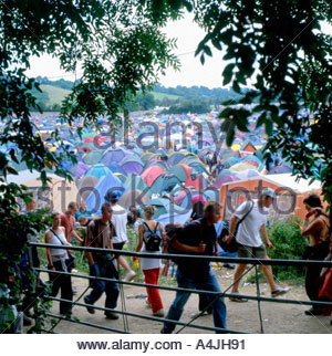 People walking past tents and gate on the Worthy Farm camping site at Glastonbury Festival in Somerset England UK    KATHY DEWITT Stock Photo