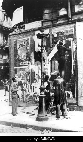Billboard with men putting up propaganda posters, Paris, World War II, 1939-1945. Artist: Unknown