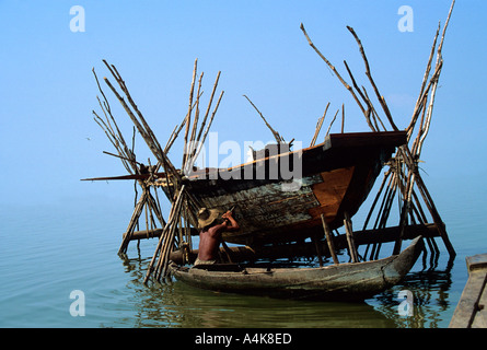 local fisherman repairs his boat on Tonle Sap Lake near the famous temples of Angkor Wat in Cambodia Stock Photo